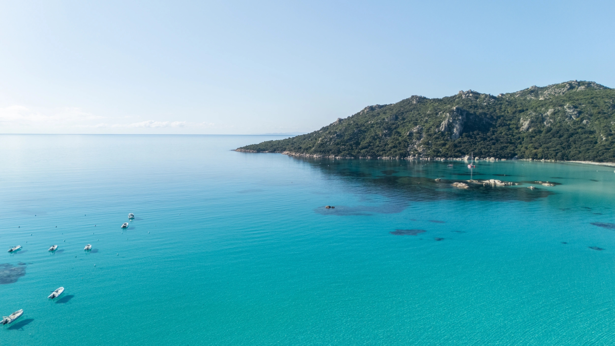 Location de bateau à Santa Giulia en Corse avec eaux turquoise et voiliers