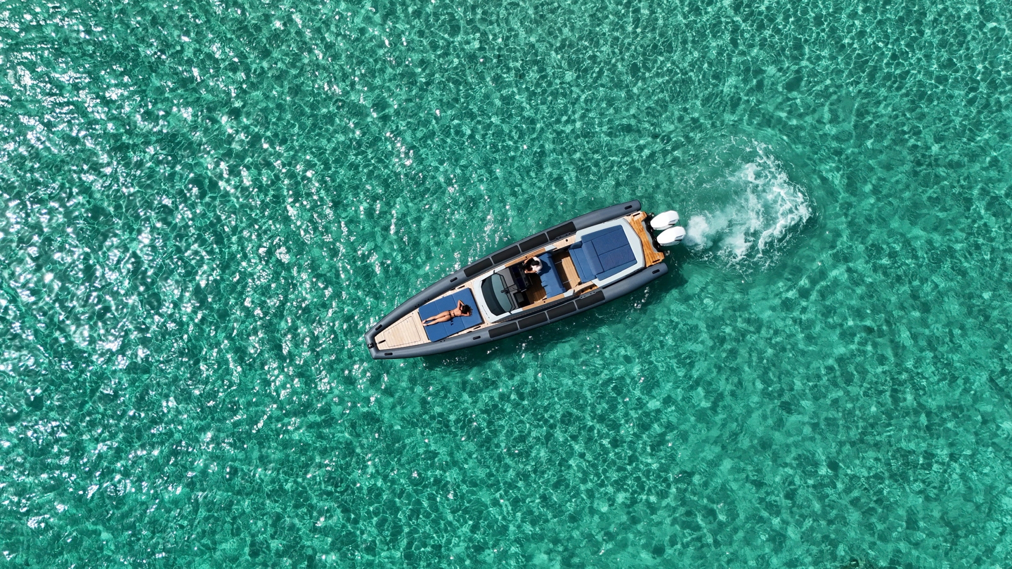 Vue aérienne d'un bateau de location moderne naviguant sur une mer turquoise cristalline