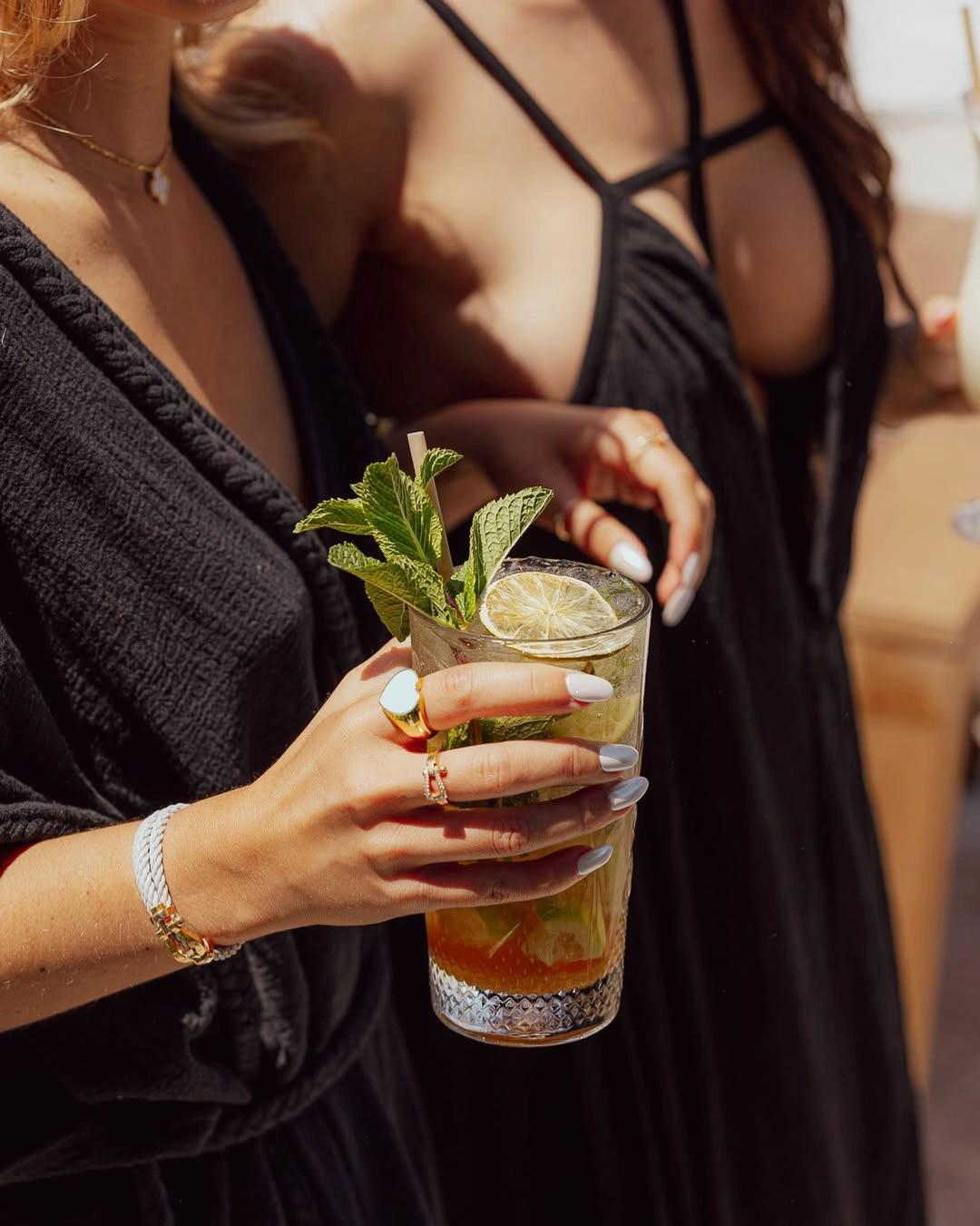 Femme tenant un cocktail mojito avec glaçons et menthe fraîche