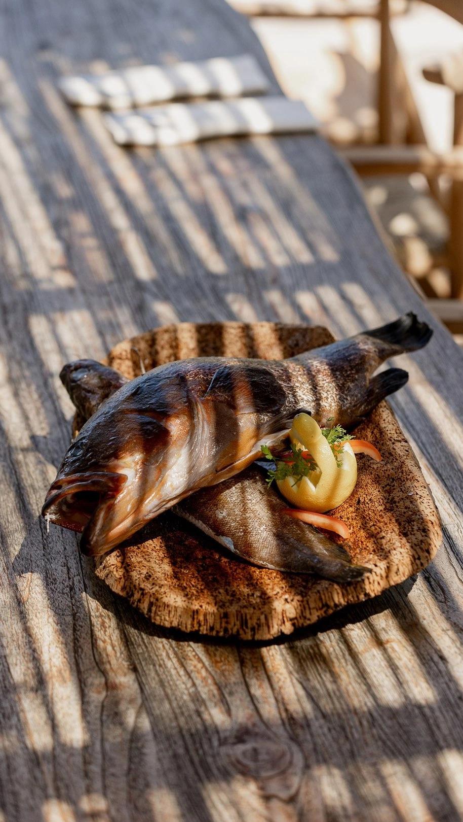 Poisson grillé présenté sur la carte du restaurant de plage à Santa Giulia