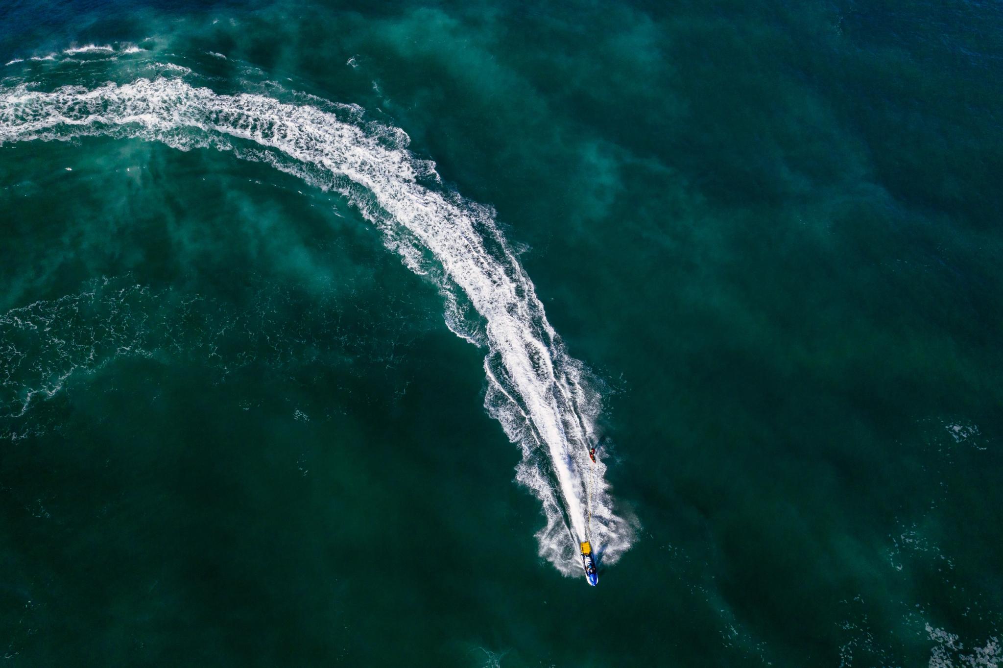 Vue aérienne d'un bateau de jet-ski naviguant en bord de mer à Santa Giulia avec ses vagues blanches écumantes