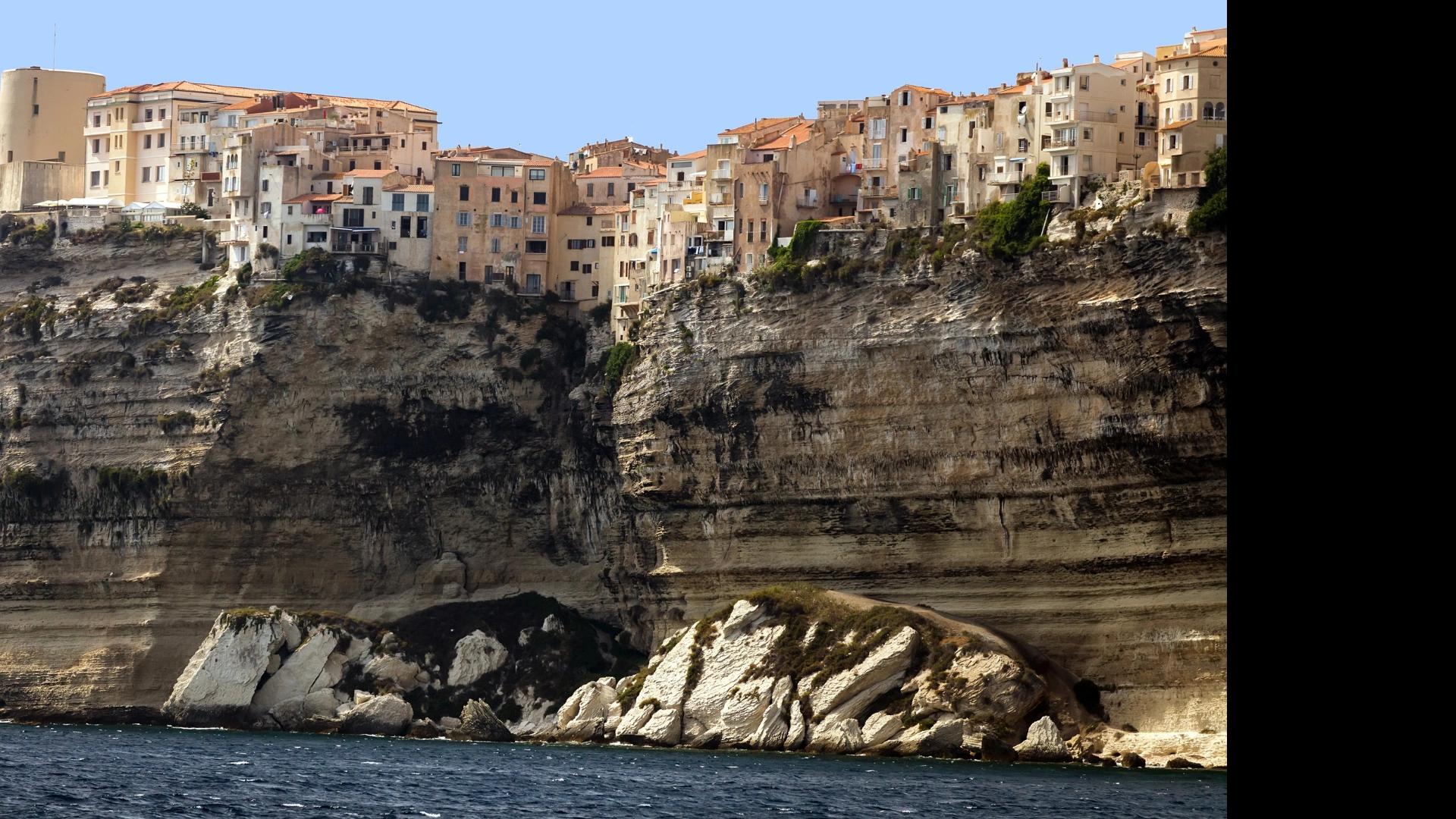 Maisons colorées perchées sur falaises rocheuses avec location de bateau à Santa Giulia en Corse