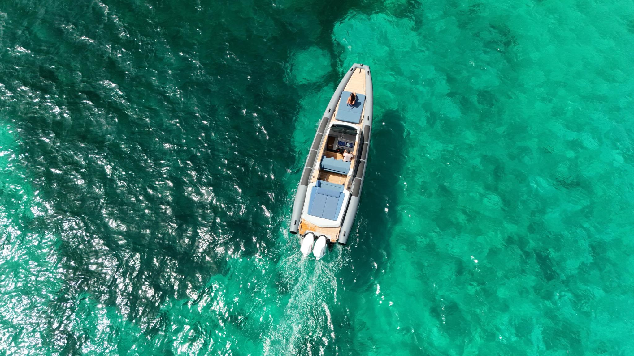 Vue aérienne d'un bateau de location blanc et orange naviguant en mer turquoise