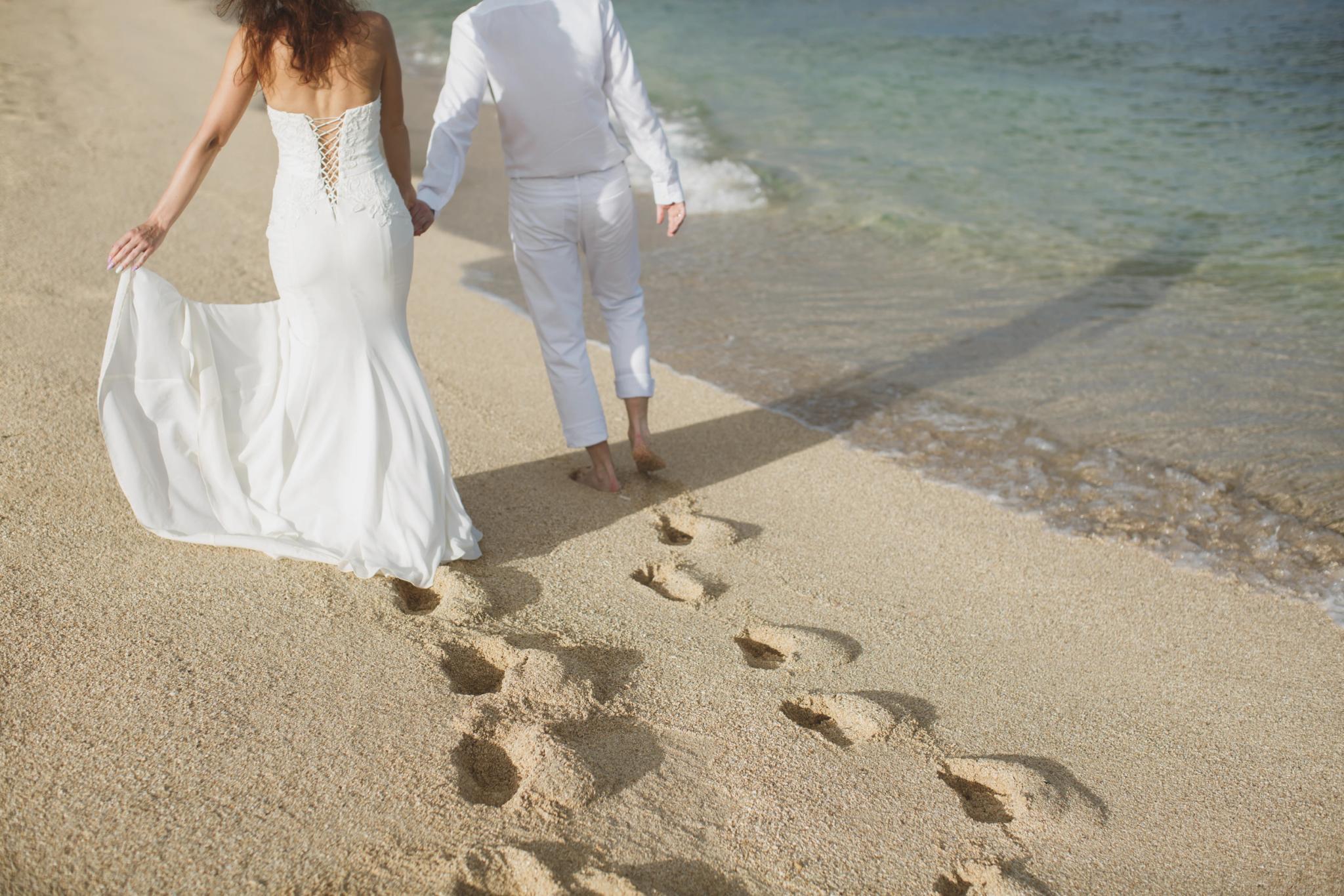 Couple marié marchant sur la plage de Santa Giulia lors d'événements privés de mariage
