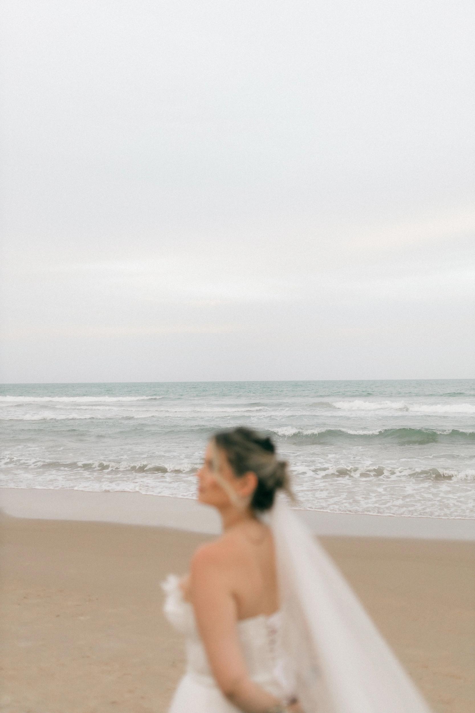 Mariée en robe blanche avec voile sur la plage de Santa Giulia pour événements privés et mariage